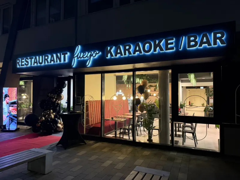 Beleuchteter Eingang des Fuego mit Schriftzug Restaurant Fuego Karaoke / Bar am Abend